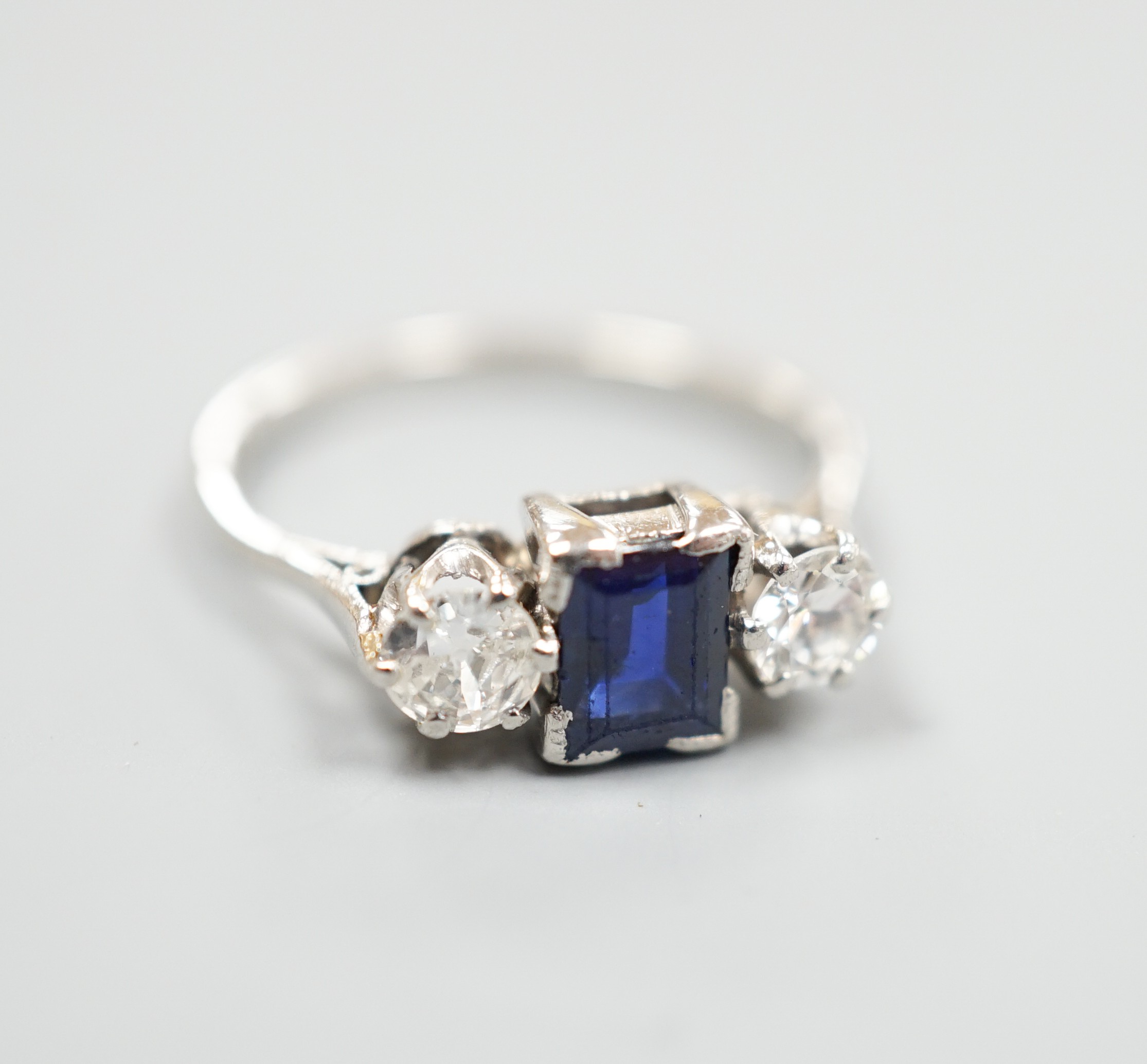 A white metal (stamped plat), sapphire and diamond set three stone ring, size K, gross weight 3.6 grams.
